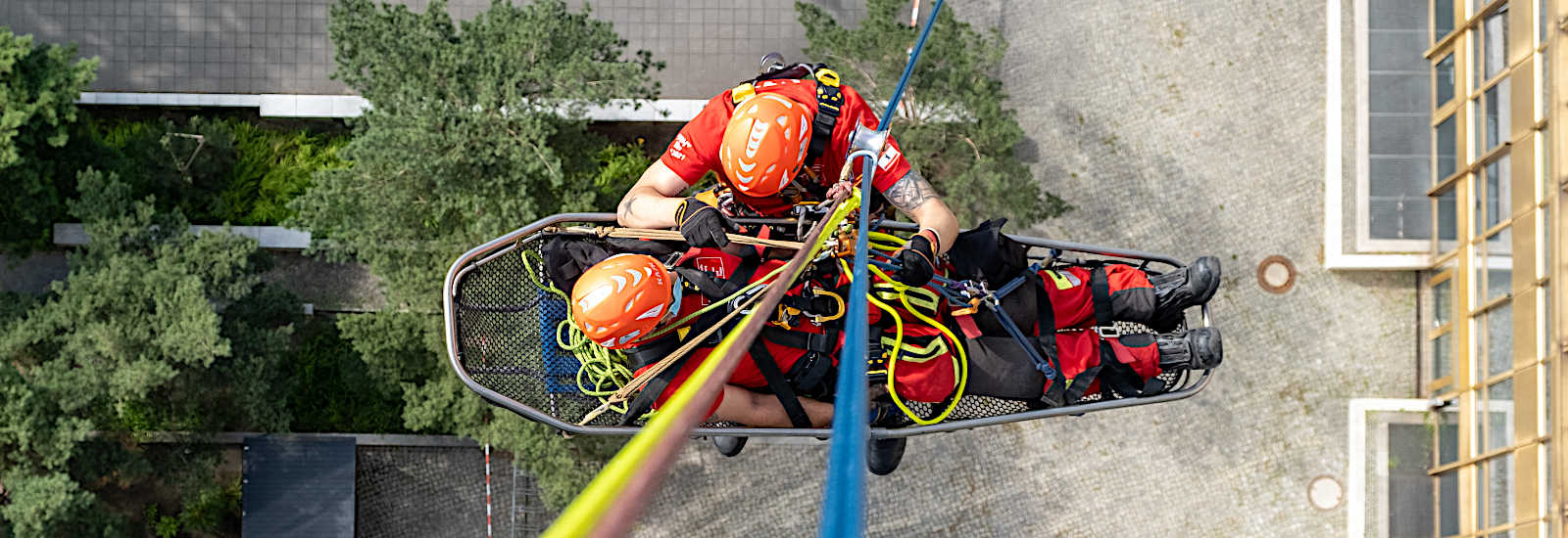 Höhenretter seilt sich mit Person in einer Trage von einem Hochhaus ab