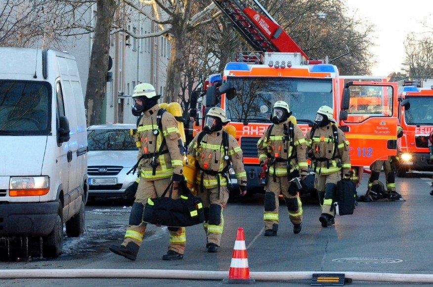 Feuerwehrleute hintereinander laufend, im Hintergrund Löschfahrzeuge