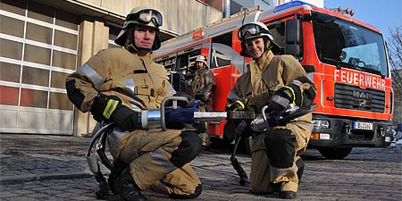 Zwei Feuerwehrleute mit technischem Gerät vor Einsatzfahrzeug
