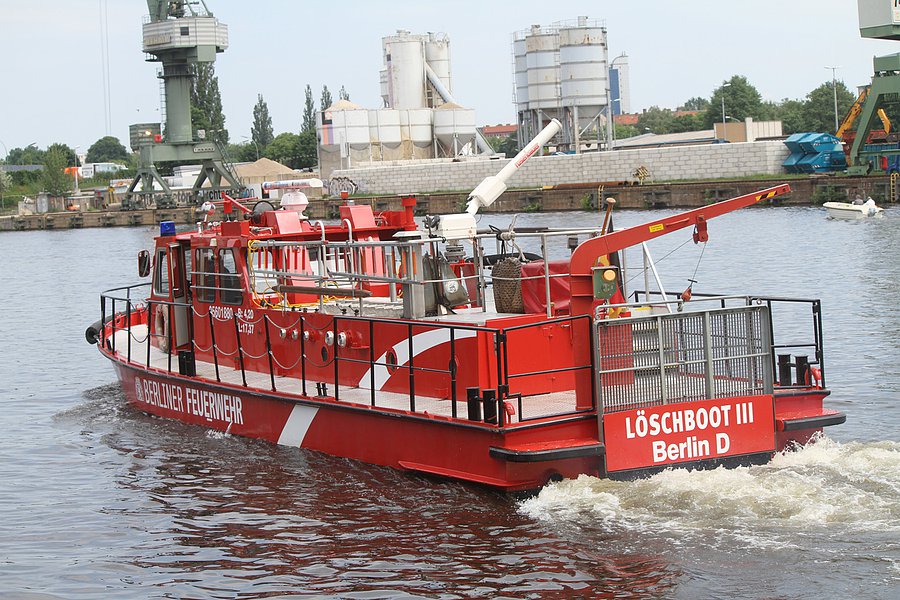 Fahrendes Löschboot mit Hafen im Hintergrund